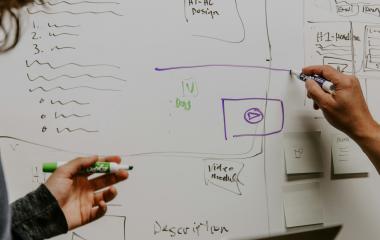 People drawing diagrams on a white board